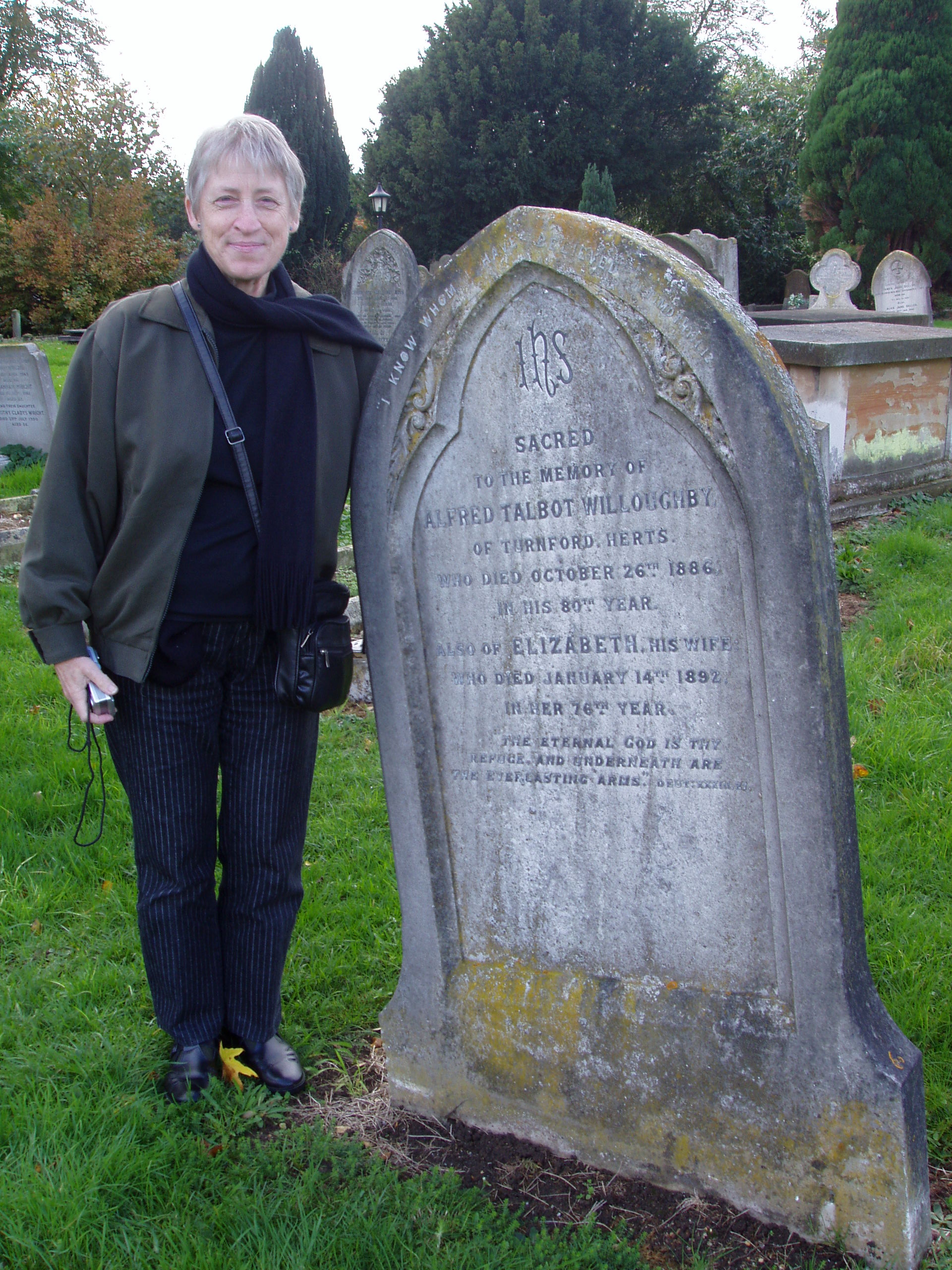 The author checks a source for death information: the gravestone of her maternal great-great-grandparents, Elizabeth and Alfred Talbot WILLOUGHBY in the Wormley Churchyard, Hertfordshire, England, on 4 November 2005. Photo: T.L., used with permission.